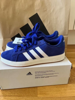 Adidas Grand Court Base 00 blå sneakers – stl 43⅓ – nya (nypris 700 kr) - Adidas Grand Court Base 00 sneakers.  Storlek: 43⅓   Färg: blå/vit   Skick: helt nya med etikett och kartong.  Klassisk Adidas-modell i mockaliknande material.   Bekväma sneakers som passar till vardag och street style.  Nypris ca 700 kr.  Kan skickas eller mötas upp i Stockholm.  #adidas #sneakers #streetwear #blå #43