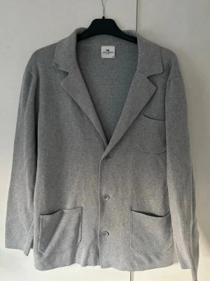 John Henric kofta herr Grå M - Sjukt snygg elegant och populär grå John Henric kofta i storlek M. Grym passform och perfekt till allt! Inga hål eller fläckar i grymt skick verkligen så gott som ny.