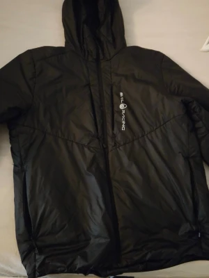 Svart vindjacka från Sail Racing - Snygg svart vindjacka från Sail Racing med huva och dragkedja framtill. Jackan har logga på bröstet och är tillverkad i ett lätt, vattenavvisande och återvunnet material. Praktiska fickor och modern passform gör den perfekt för blåsiga dagar.Nypris 2500kr men säljer den för 700kr. Varsamt använd men inga fel på den. Säljer då den inte kommer till användning. 