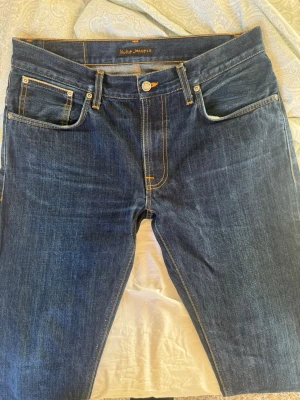 Selvage Nudie Jeans - Vi säljer dessa fina Dry Selvage nudie Jeans, i modellen Thin Finn. Jeansen är i fint skick, med en lagning vid ena bälteshällan (se bild). Storlek W34 L36, men skulle säga att de inte är så stora som det låter. Killen på bilden är 186 och jeansen passar bra. Jeansen är perfekta för att användas och få fades, och de har redan börjat få lite lite fades. Hör av dig vid frågor! 