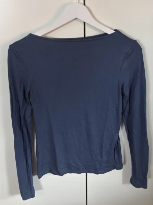 Mörkblå långärmad topp - En stilren mörkblå långärmad topp med rak halsringning. Toppen har en enkel och klassisk design som passar till många olika outfits. Tillverkad i mjukt material för en bekväm känsla.