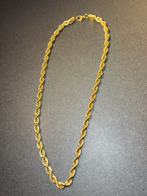 Guldfärgat tvinnat halsband - Snyggt guldfärgat halsband med tvinnad kedja som ger en cool och trendig look. Halsbandet har en klassisk karbinhake och är gjort i metall med glansig finish. Perfekt för att lyfta vilken outfit som helst.