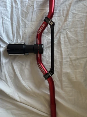 Röd styre till moped från Voca, Str8 bar - Säljer ett rött styre till moped från Voca med svart förstärkningsstag från STR8. Styret är gjort i aluminium och har en sportig design med vita detaljer och loggor. Perfekt för dig som vill uppgradera din moped med en snygg och robust look.