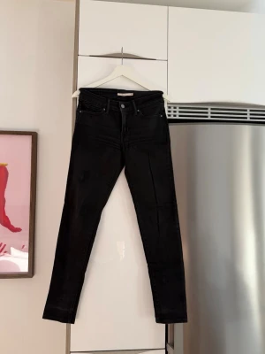Svarta skinny jeans från Levi's - Säljer ett par svarta skinny jeans från Levi's med klassisk femficksmodell och hög midja. Jeansen har smal passform hela vägen ner och är tillverkade i stretchigt denimtyg för extra komfort.