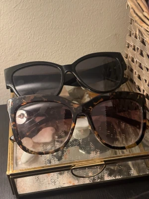Två par stora solglasögon - En kostar 60 om köper båda kostar de 145. Säljer två par trendiga solglasögon med stora bågar. Ett par är helsvarta med klassisk look och det andra har ett sköldpaddsmönster i bruna toner. Båda har breda skalmar och ger en cool vibe till din outfit.