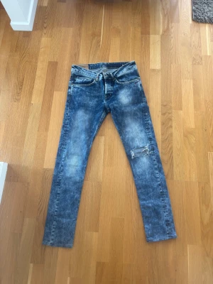 Dondup  - Säljer ett par blå dondup jeans med slitningar och ett hål på ena knät. 