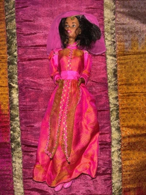 Vintage Barbie princess docka – fantasyklänning från 90/00-tal - Säljer en vintage Barbie-docka från Mattel i prinsess/fantasy-stil, troligen från sent 90-tal eller tidigt 2000-tal. Dockan har långt mörkt hår och bär en detaljrik rosa klänning med gulddetaljer, matchande huvudplagg/slöja, smycken och rosa skor.  Mycket vacker och unik docka med klassisk vintage Barbie-känsla. Smink och ansikte är fint bevarade och dockan gör sig perfekt för samling eller display.  Alla delar som syns på bilderna ingår.  Skick: Mycket bra