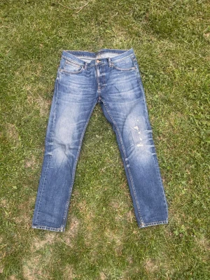 Blå slim fit jeans från Nudie - Snygga blå slim fit jeans från Nudie med klassisk femficksdesign och slitna detaljer på benen. Jeansen har orangea sömmar och läderpatch bak i midjan. Perfekta för en avslappnad och trendig stil. Modellen Lean Dean 