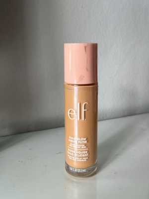 e.l.f. Halo Glow foundation - Säljer en e.l.f. Halo Glow Liquid Filter foundation. Färgen är medium beige med varm underton och ger en glowig finish. Märkena på korken är från tejp som suttit på. Den är som ny, bara använd några fåtal gånger. Innehåller 31,5 ml.