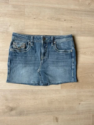 Blå Mini Y2K Skirt Vigoss Jeanskjol Embroidery - Mycket fin kjol i blå färg. Kjolen är i mycket bra skick och sparsamt använda. |  Äkta som allt annat jag säljer! ✅ |  Storlek: L / 40  | Skick: Mycket Bra Skick - har tyvärr några väldigt små fläckar på baksidan (SE SISTA BILD) men ska gå bort med rätt medel. | Färg: Blå | Märke: Vigoss | Modell: Kjol |   Hör gärna av dig vid frågor så svarar jag så fort jag kan! 😁 |  (SKU - 150)
