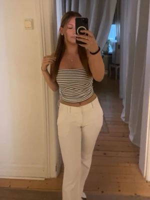 Vita lågmidjade kostymbyxor  - Säljer ett par vita kostymbyxor lågmidja. Perfekta för en clean och stilren look. Har slits ner till, lite för långa för mig som är 159, lite slitna ner till där av priset, går säkert bort i tvätten med fläck borttagning eller att klippa bort. 