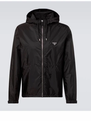 Svart vindjacka från Prada - Snygg svart vindjacka från Prada med dragkedja framtill, huva med dragsko och elastiska muddar. Jackan har en minimalistisk design och det ikoniska Prada-emblemet på bröstet. Tillverkad i glansigt, lätt material som ger en modern look.