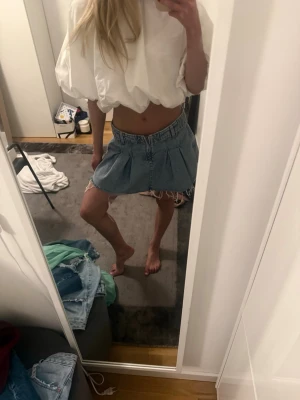 Super cool jeans kjol  - Trendig ljusblå jeanskjol med plisserade detaljer och rå, fransig kant nertill. Kjolen har klassisk jeansmidja med hällor och dragkedja framtill. Perfekt för en avslappnad och cool stil.