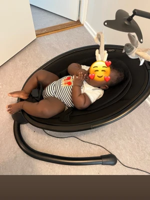 Elektrisk babysitter med båge - Elektrisk babysitter i svart med mjuk sits och båge med mjukisdjur. Modern och stabil design med säkerhetssele, lugnande melodier och justerbar vaggning. Endast använd 3 gånger då mitt barn inte trivdes i den. En leksak saknas på bågen men jag ska försöka hitta den innan försäljning.