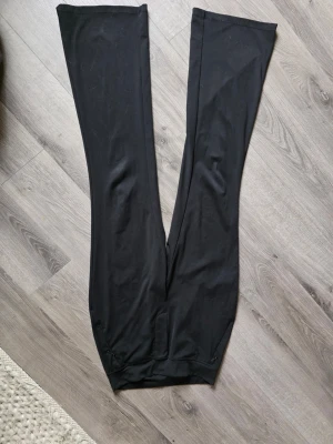 Svarta leggings bed bootcut från Ninepine - Säljer ett par svarta leggings med  vida bendlut och hög midja. Materialet är stretchigt och mjukt, perfekt för en avslappnad och trendig look. Inga synliga detaljer eller loggor, enkel och stilren design. Fickor med blixtlås. Storlek S men passar M