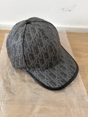 Grå keps - Snygg grå keps med monogram över hela. Perfekt inför sommaren och soliga dagar. Hör av er vid frågor. Pris går att diskutera.