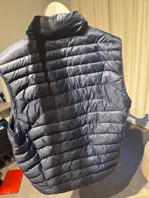 Mörkblå dunväst med dragkedja från polo raulph lauren  - Snygg mörkblå dunväst från polo Ralph lauren med hög krage och två dragkedjeförsedda fickor framtill. Västen har quiltad design och justerbar nederkant med dragsko. Perfekt för lager-på-lager och håller dig varm under kyliga dagar. Sommar, Dalily wear (pris kan diskuteras)