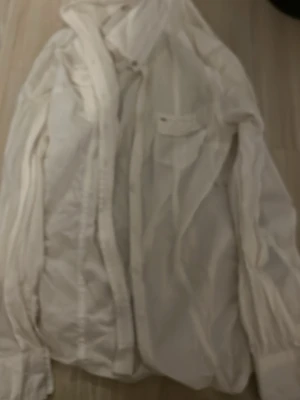 Vit skjorta från Hilfiger Denim XS - Klassisk vit skjorta från Hilfiger Denim i storlek XS. Skjortan har långa ärmar, bröstficka med knapp och diskreta ränder i tyget. Perfekt för en clean och stilren look. Materialet känns lätt och bekvämt.