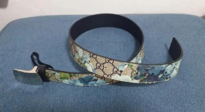 Gucci blommigt bälte med blå detaljer - Snyggt bälte från Gucci med klassiskt GG-mönster och blommigt tryck i blå och gröna nyanser. Bältet har en silverfärgad spänne och är gjort i skinn med canvas-yttermaterial. Perfekt för att lyfta vilken outfit som helst. Köpt äkta från Vestiaire, 95 cm lång och 3,5 cm bred. Bältet är sällsynt och svårt att få tag på.