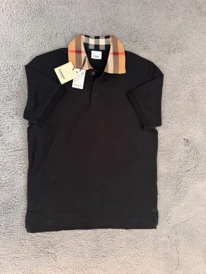 Burberry piké - Säljer en helt ny och stilren svart burberry piké. Storleken är i S. Säljer den då den inte passar mig.