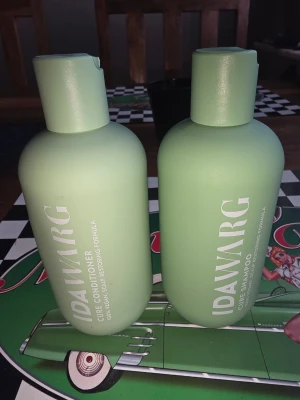 Ida Warg Cure Shampoo & Conditioner - Säljer ett set med Ida Warg Cure Shampoo och Cure Conditioner. Båda flaskorna är ljusgröna och har en rund, stilren form med vit text. Produkterna är av plast och har praktiska flip-top lock. Perfekt för dig som vill ha hårvård med skonsam och vårdande formula.