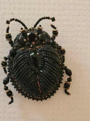 Handgjord brosch – Skalbagge - Elegant och detaljrikt handbroderad brosch i form av en skalbagge. Tillverkad med svarta glaspärlor, gnistrande kristaller och vackra detaljer i guldfärg. Varje detalj är omsorgsfullt sydd för hand, vilket gör broschen unik. 🖤 Handgjord 🖤 Broderad med pärlor och kristaller 🖤 Unik design 🖤 Fäste på baksidan En iögonfallande accessoar som passar perfekt på kavaj, kappa, väska eller sjal.