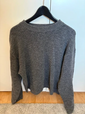 Mörkgrå stickad tröja - En enkel och stilren mörkgrå stickad tröja från H&M med rund halsringning och långa ärmar. Skriv för mer bilder!