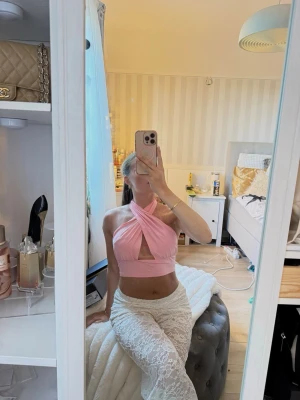 Rosa omlott croppad halterneck topp - Snygg rosa croppad topp med omlott-design och halterneck. Toppen har en öppen rygg och är tillverkad i ett mjukt, stretchigt material som känns bekvämt mot huden. Perfekt för dig som vill sticka ut med en trendig och ungdomlig stil.