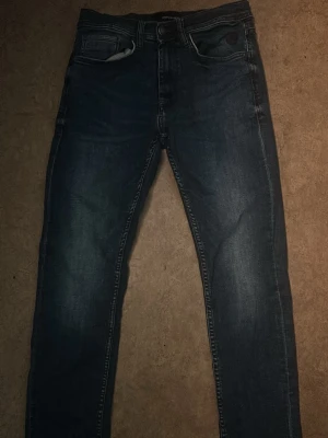 Mörkblå jeans från Blend - Snygga mörkblå jeans från Blend med klassisk femficksdesign och smal passform. Jeansen har slitningar och kontrastsömmar som ger en cool look. Perfekta för dig som gillar en stilren men avslappnad vibe. Obs!!! Kolla sista bilden, två små hål som knappt syns när man har på sig dom. Hör gärna av dig!