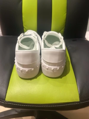 Pris går att diskutera/kan byta -  Snygga vita sneakers från Valentino Garavani med svarta detaljer och nitar baktill. Skorna har vita skosnören, svart panel med vita prickar på sidorna och är tillverkade i läder. Perfekta för dig som gillar exklusiv och trendig streetstyle.
