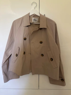 Kort beige trenchcoat från ONLY - Trenchcoat från only i storlek m. Den har dock lite deffekt på insidan men inget som syns när man har på sig den 