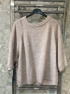 Beige stickad tröja med trekvartsärm - Mysig beige stickad tröja med bred ribbad rund halsringning och trekvartsärmar. Tröjan har en avslappnad passform och är perfekt för lager-på-lager. Materialet känns mjukt och passar bra till jeans eller kjol.