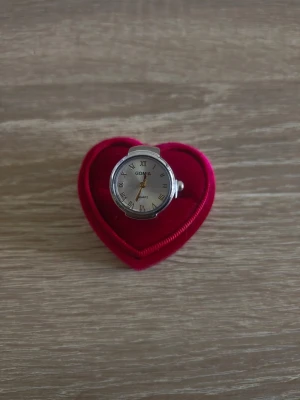Silverfärgad ringklocka - Unik ringklocka i silverfärg med klassisk urtavla och romerska siffror. Klockan har ett elastiskt band som gör att den sitter bekvämt på fingret. Perfekt accessoar för dig som vill sticka ut med något annorlunda.