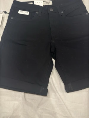 Svarta shorts från Selected Homme xs - Snygga svarta shorts från Selected Homme i klassisk femficksmodell. Gjorda i 100% bomull med uppvikta benslut och knappgylf. Perfekta för en stilren och enkel look under varmare dagar.