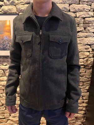 Mörkgrå overshirt från asos  - Stilren mörkgrå overshirt med dragkedja framtill och två bröstfickor med lock och knapp. Klassisk krage och raka ärmar. Materialet ser ut att vara mjukt och lite tjockare, perfekt för lager på lager. Passar till jeans eller chinos för en avslappnad look.