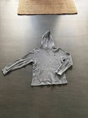 Grå Polo Ralph Lauren hoodie med huva och magficka - Säljer en enkel och stilren grå Polo Ralph Lauren hoodie. Den är i mycket bra skick:)