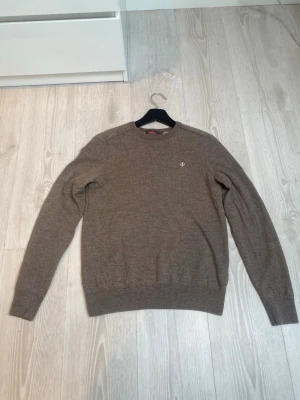 Brun merinoulltröja från Morris - Brun stickad tröja från Morris i 100% merinoull. Rund hals, ribbade muddar och nederkant samt liten broderad logga på bröstet. Enkel och klassisk modell som är lätt att matcha. Inga defekter pris kan diskuteras vid snabb affär! Tröjan är M men passar även S