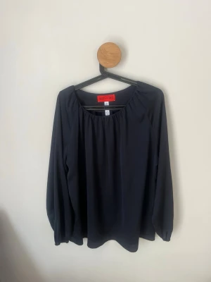 Marinblå blus och löstsittande armar från WHYRED - Stilren svart blus från WHYRED med rundad halsringning och långa, löst sittande ärmar. Blusen har ett mjukt, lätt material som faller snyggt och passar perfekt till både jeanskjol och kjol.