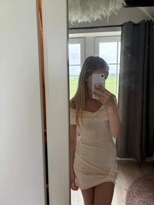 Jättefin offshoulder kortklänning - Snygg ljusrosa/beige tight kortklänning med offshoulder-design och draperad detalj vid ena benet. Köpt för typ två år sedan på Asos och använd 2-3 ggr.