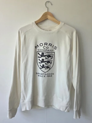 Vit t-shirt från Morris Company - Klassisk vit t-shirt från Morris Company i mjuk bomull. Enkel och stilren design med rund halsringning och diskret logga i nacken. Perfekt basplagg för alla tillfällen och lätt att matcha med andra plagg.
