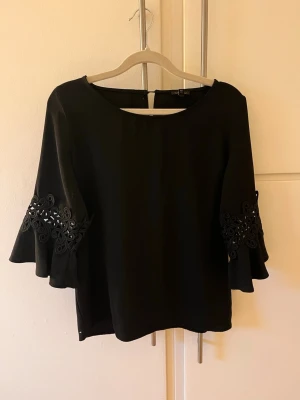 Svart blus med volangärm och spetsdetalj - Snygg svart blus med volangärmar och spets.