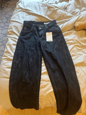 Vida svarta jeans från Bershka (brand new with tags) - Säljer ett par svarta jeans från Bershka med bred passform och hög midja. Jeansen har klassiska fem fickor, vita kontrastsömmar och raka, vida ben. Perfekta för en trendig och avslappnad stil.