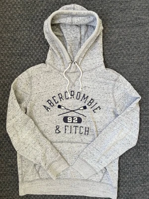 Grå hoodie från Abercrombie & Fitch (sällsynt) - Säljer nu denna sjukt snygga Vintage 2000s Abercrombie & hoodie! Passar till allt och har en perfekt passform. Säljs ej längre i butik och är därav mycket eftertraktad😊 passar S perfekt ! Skriv vid funderingar 🤝