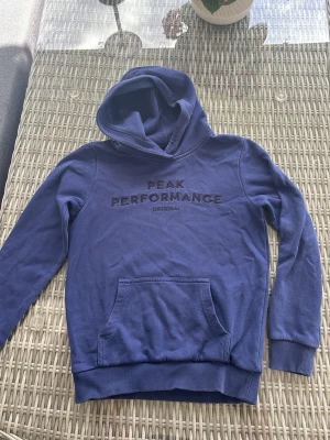 Blå hoodie från Peak Performance - Snygg blå hoodie från Peak Performance med broderad logga på bröstet. 