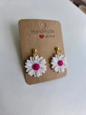 Handgjorda örhängen med vita prästkragar  - Supersöta handgjorda örhängen i form av vita prästkragar med rosa mitt och guldfärgade detaljer. Perfekta för dig som vill ha något unikt i öronen nu i sommar! Gjorda för hand av mig i polymerlera. 
