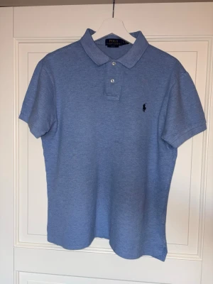 Blå pikétröja från Ralph Lauren - Klassisk blå pikétröja från Ralph Lauren. Storlek ”Large” men är mindre i storlek, motsvarar ”Medium”. 