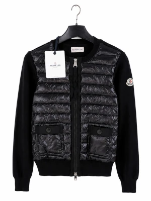 Svart cardiganjacka från Moncler - Snygg svart cardiganjacka från Moncler med quiltad, glansig front och två fickor med knappstängning. Ärmar och rygg är i mjuk stickad kvalitet. Dragkedja framtill och Moncler-logga på ärmen ger en exklusiv touch. Perfekt för dig som gillar stilrena och sportiga plagg.