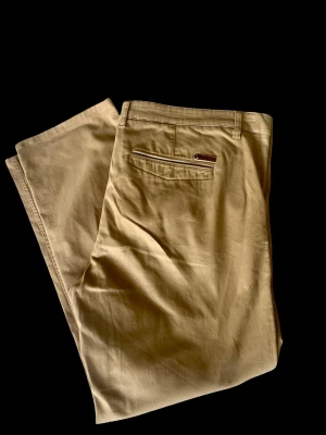 Beige chinos NN07 - Snygga beige chinos (storlek 36) med raka ben och klassisk passform som knappt är använda. Byxorna har bälteshällor, två sidofickor och en bakficka med knappdetalj. Tillverkade i mjukt bomullstyg som ger en avslappnad men stilren look.