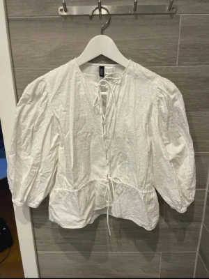 Vit blus med puffärm  - Söt vit blus från H&M Divided med puffiga trekvartsärmar och knytband fram. Helt oanvänd 