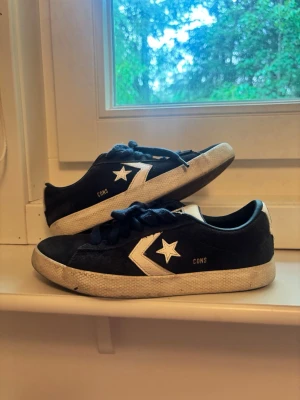 Mörkblå Converse CONS sneakers - Snygga mörkblå Converse CONS sneakers i mocka med vita detaljer och klassisk stjärnlogga på sidan. Skorna har vita sulor och mörkblå skosnören. Perfekta för dig som gillar streetwear och vill ha en ikonisk look.